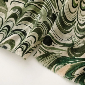 Detailed view of emerald green paisley pattern on lightweight cotton linen scarf with frayed edges