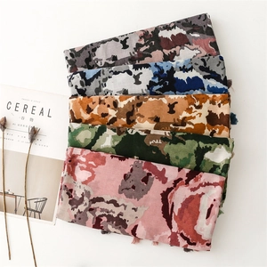 Flat lay of colorful abstract floral scarves with fringe tassels and lifestyle magazine