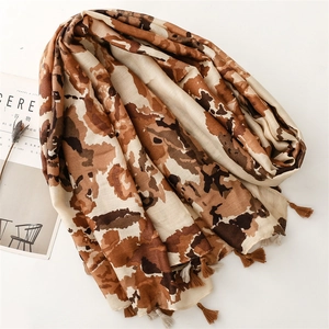 Detailed view of earth-tone leopard print scarf with handmade fringe on a minimalist background