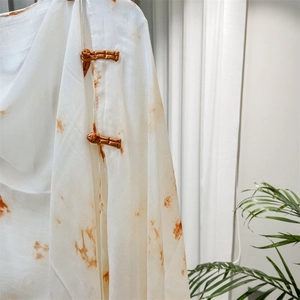 Detail of white cotton shawl featuring traditional buttons and orange marble tie-dye pattern