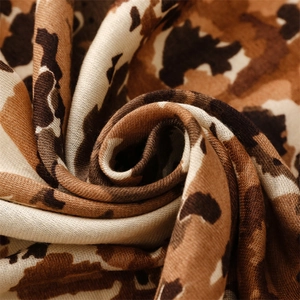 Detailed macro shot of leopard print scarf fabric showing thick woven texture and tassels