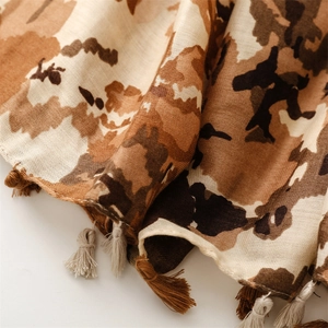 Detail of soft cotton-linen scarf with camouflage pattern and handmade fringe edges