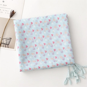 Detail of light blue scarf featuring multi-colored heart prints and elegant fringe edges