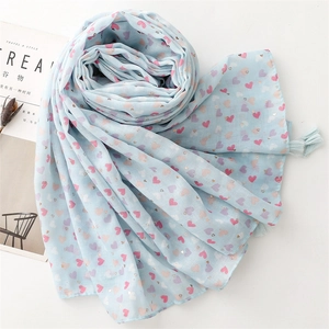 Detail of light blue scarf featuring gold heart prints and fine tassel edges