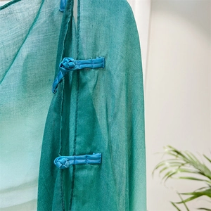 Detail of emerald green linen shawl featuring traditional Chinese blue knot buckle closure
