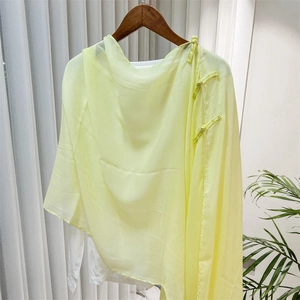 Detail of light yellow sheer shawl with traditional Chinese knot button on a hanger