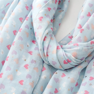 Close-up of light blue scarf with colorful heart patterns and gold foil detail