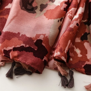 Detailed view of soft abstract print scarf with handmade pink and brown tassels