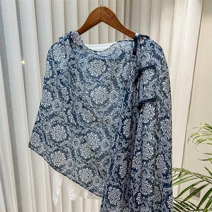 Detail of blue floral shawl with traditional Chinese frog button on a wooden hanger