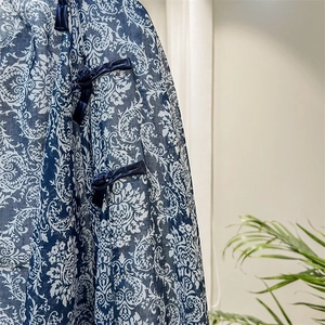 Detailed view of dark blue silk scarf featuring traditional Chinese frog button and floral pattern