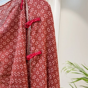 Detailed macro of red cotton-linen shawl with white star prints and manual silk frog button