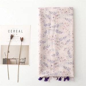 Sciarpa floreale rosa pastello con motivi blu e nappe su uno sfondo bianco minimalista