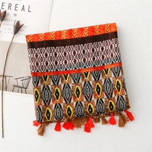 Detail of bohemian scarf featuring geometric patterns and soft orange fringe tassels