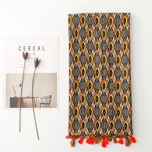 Detail of geometric pattern scarf with textured fabric and vibrant orange tassels