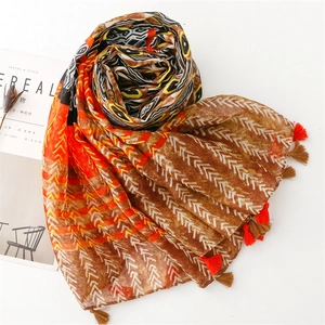 Detailed close-up of ethnic geometric scarf with orange tassels and tribal patterns