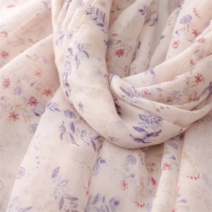 Dettaglio di una sciarpa leggera rosa con motivi di foglie viola e piccoli fiori rossi