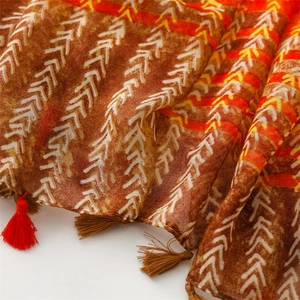 Close-up of geometric arrow pattern weave and colorful tassels on an ethnic scarf