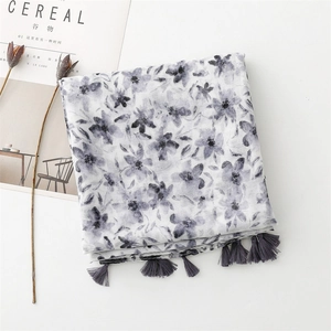 Close-up of beige linen shawl with grey floral watercolor print and decorative tassels
