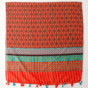 Detailed view of bohemian geometric scarf with vibrant orange tones and colorful tassels