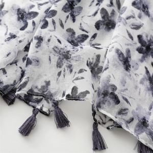 Detail of floral ink print on light breathable scarf with purple tassel fringe