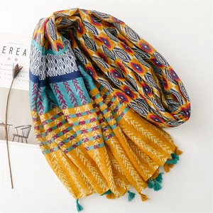 Detail of ethnic geometric patterns and tassels on a lightweight mustard yellow shawl