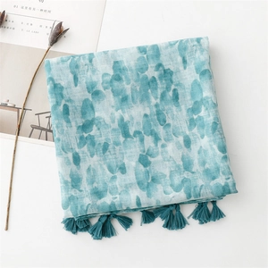 Close-up of teal cotton linen scarf featuring artistic ink wash print and tassel fringe