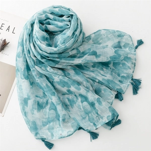 Close-up of light blue linen scarf with abstract watercolor patterns and fringe trim