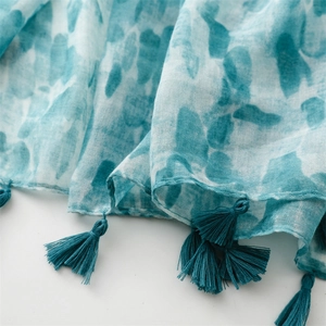 Detailed close-up of blue and white gradient linen scarf with fringe tassels