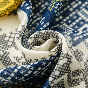 Détail macro du motif ethnique au point de croix sur le textile du foulard bleu et jaune