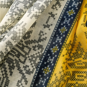 Gros plan des motifs ethniques en point de croix sur un foulard léger en coton et lin à franges