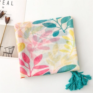 Détail de l'écharpe rose avec imprimés de feuilles colorées et pompons turquoise vifs
