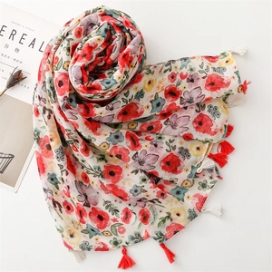 Flat lay of pink floral scarf with red tassels, styled with a magazine and dried flowers