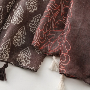 Close-up of geometric ethnic patterns and tassel details on a brown cotton linen scarf