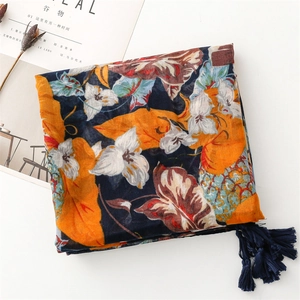 Close-up of lightweight navy scarf with ginger leaves, white flowers and fringe details