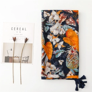 Detail of tropical scarf with pineapple and lily prints, navy tassels, and light fabric