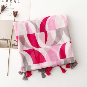 Close-up of pink and white geometric scarf with decorative fringe tassels and soft texture