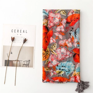 Macro detail of tropical scarf featuring pink flowers, pineapple prints and grey tassels
