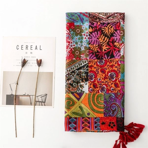 Detail of red Bohemian shawl featuring paisley prints, linen texture, and tassel fringe