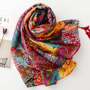 Detail of bohemian red scarf with floral paisley prints and delicate tassel accents