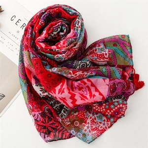 Macro detail of red bohemian cotton scarf with geometric floral patterns and tassels