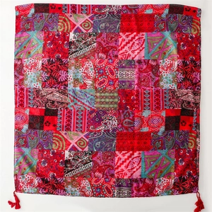 Close-up of red bohemian scarf with patchwork paisley patterns and ethnic fringe tassels