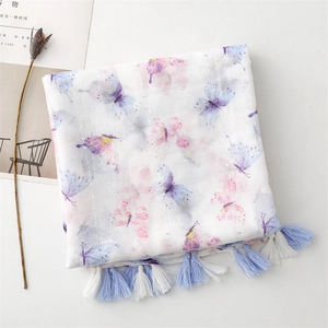Detail of a light cotton linen scarf with butterfly prints and long blue white tassels