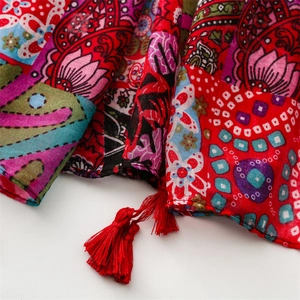 Detail of red Bohemian scarf featuring paisley patterns and long crimson tassel fringe