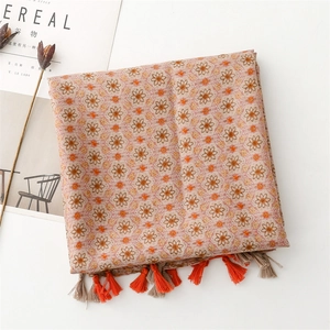 Detail of light brown floral scarf with orange tassels and delicate linen texture