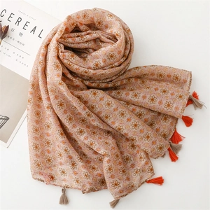 Detail view of light pink floral silk scarf with orange flower prints and fringe tassels