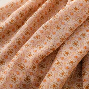 Macro detail of floral print fabric with orange small flowers and geometric pattern