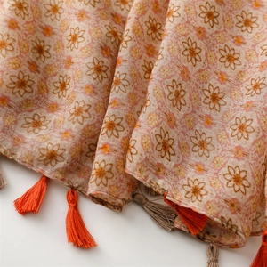 Detail of floral print scarf with orange tassels and bohemian sun flower pattern