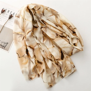 Macro detail of cotton-linen scarf with gold foil floral print and frayed edges