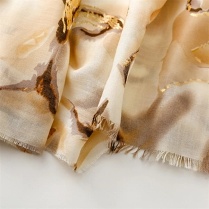 Detailed view of abstract floral gold foil printing on cotton linen shawl with frayed edges