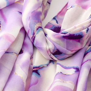 Detailed macro shot of floral print chiffon shawl with golden metallic accents and frayed edge